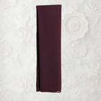 Brown clothing rack with a coffee fabric draped over it against a white wall.