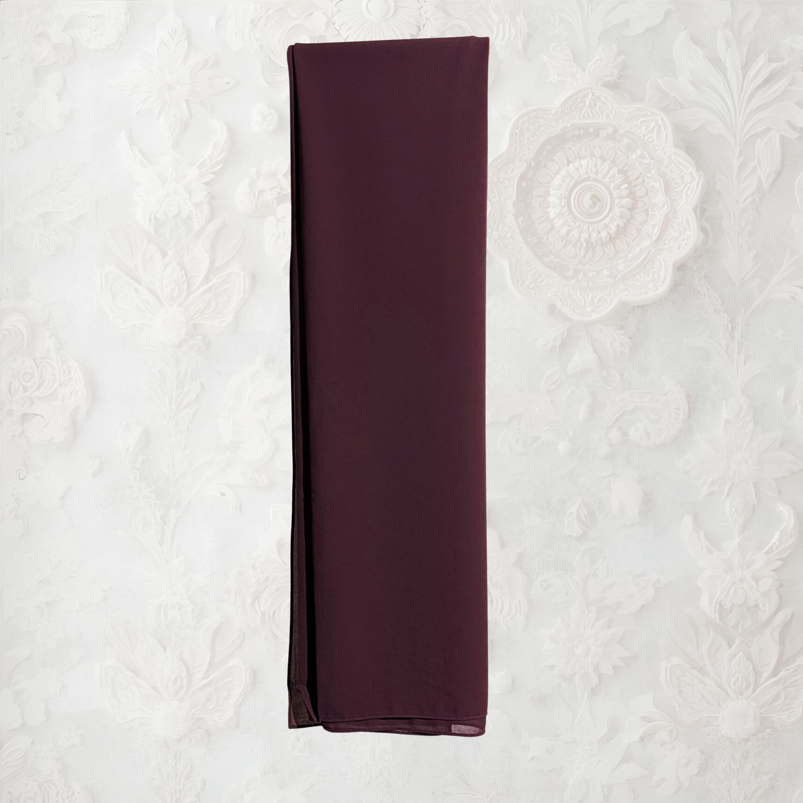 Brown clothing rack with a coffee fabric draped over it against a white wall.