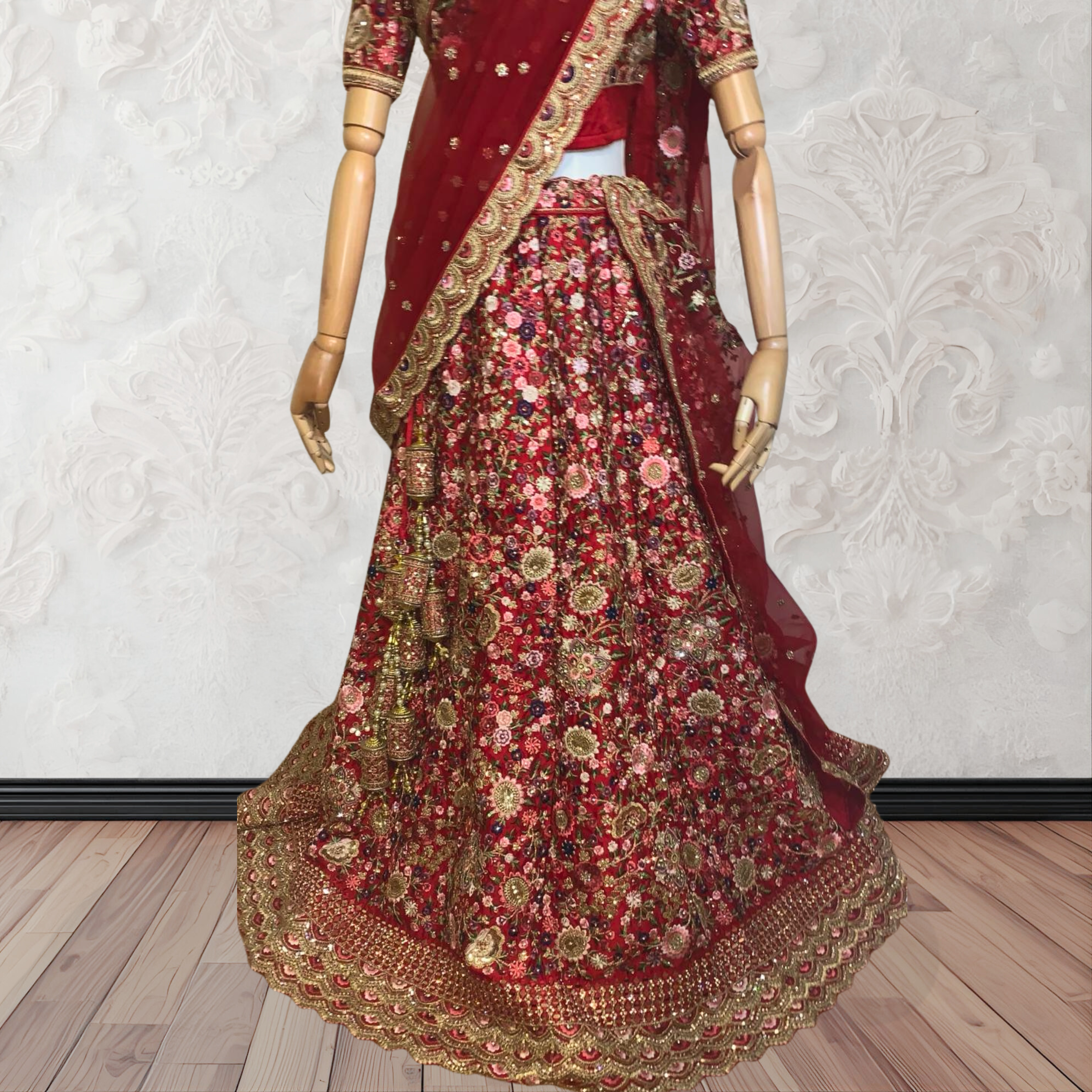This exquisite red lehenga choli crafted from luxurious raw silk showcases intricate resham, zardosi, beads, sequins, and cut dana floral embroidery. The heavily embellished hemline and delicate cream butti accents enhance its sophisticated charm. Complete with a matching embroidered net dupatta featuring floral buttis and an elegant border, and a stitched blouse piece adorned with coordinating floral motifs, for wedding and bridal, pakistani, bangladeshi, indian, sri lankan.