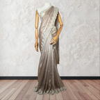 Mannequin wearing a beige saree with lace details against a white wall.