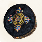 Round black embroidered pouch with colorful floral patterns on a beige background