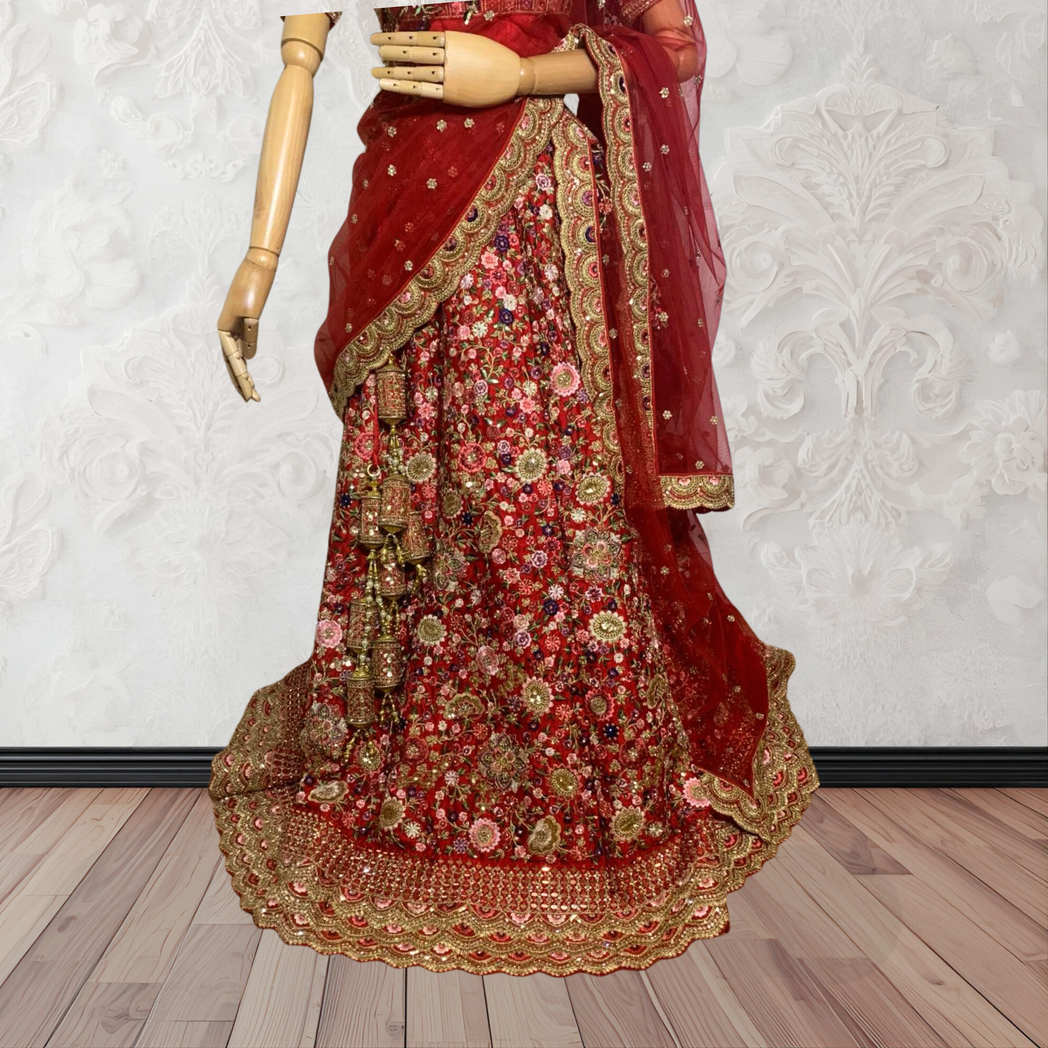 This exquisite red lehenga choli crafted from luxurious raw silk showcases intricate resham, zardosi, beads, sequins, and cut dana floral embroidery. The heavily embellished hemline and delicate cream butti accents enhance its sophisticated charm. Complete with a matching embroidered net dupatta featuring floral buttis and an elegant border, and a stitched blouse piece adorned with coordinating floral motifs, for wedding and bridal, pakistani, bangladeshi, indian, sri lankan.