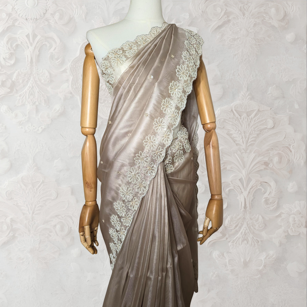 Mannequin wearing a beige saree with lace details against a white wall.