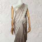 Mannequin wearing a beige saree with lace details against a white wall.
