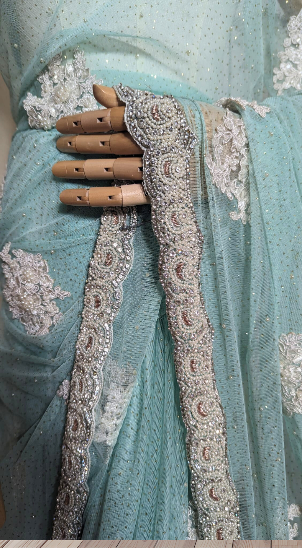 Light blue saree with intricate silver embroidery on a wooden floor.