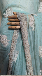 Light blue saree with intricate silver embroidery on a wooden floor.