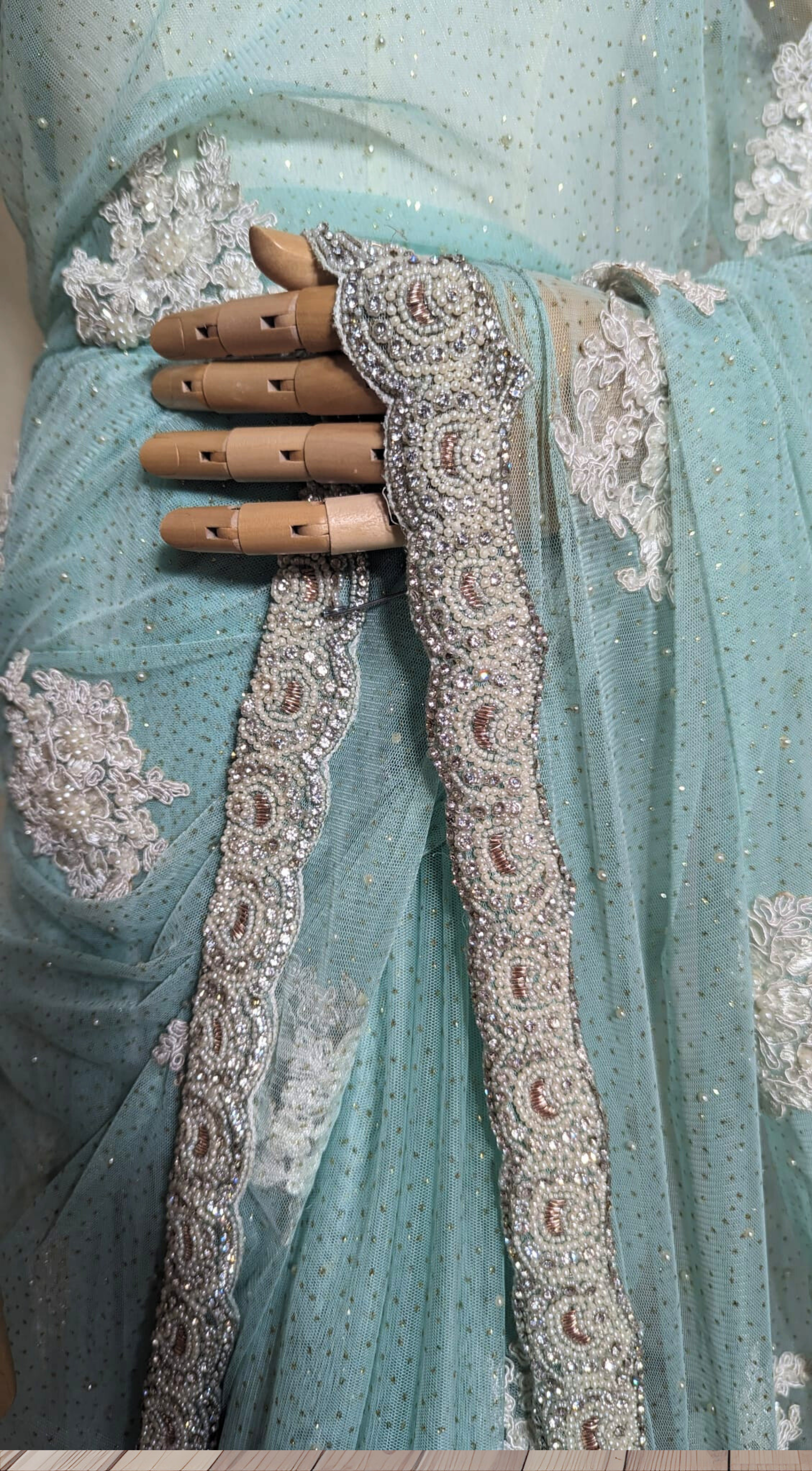 Light blue saree with intricate silver embroidery on a wooden floor.