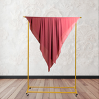 Yellow clothing rack with a red fabric draped over it against a white wall.
