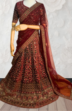Maroon Lehenga with gold embroidery on a mannequin against a white wall. traditional desi, Indian, Pakistani, Bangladeshi, Sri lankan bridal ware for wedding. 