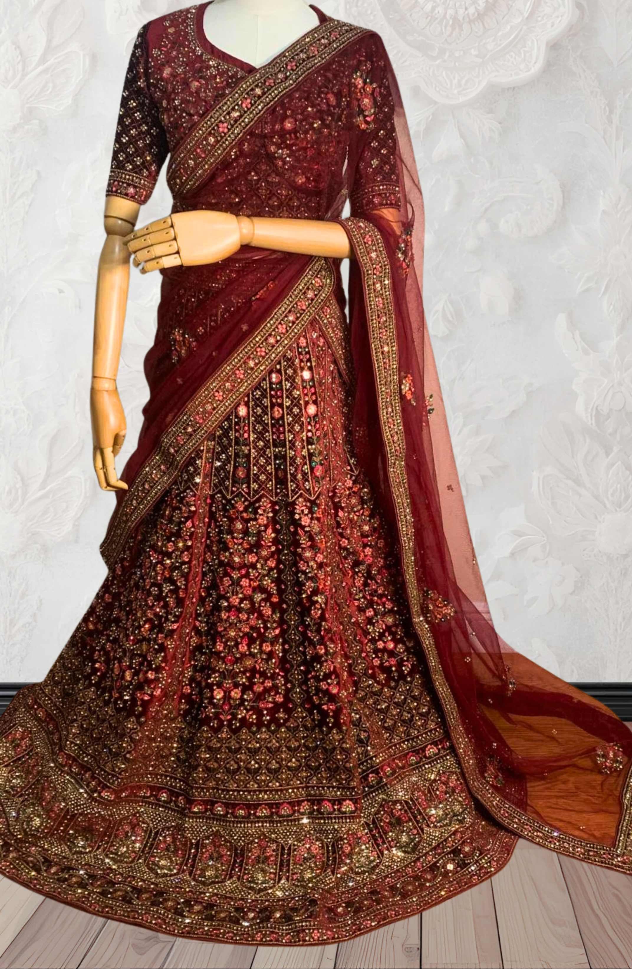 Maroon Lehenga with gold embroidery on a mannequin against a white wall. traditional desi, Indian, Pakistani, Bangladeshi, Sri lankan bridal ware for wedding. 