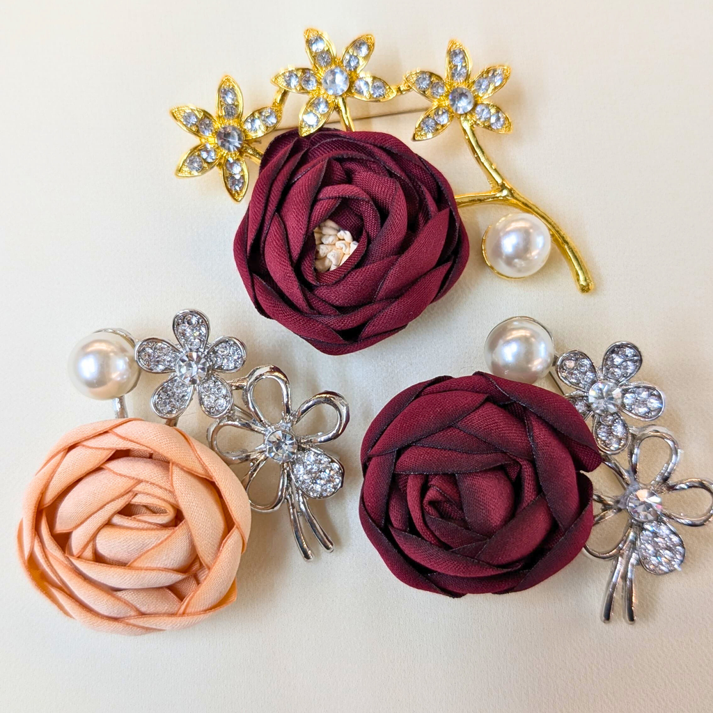 Set of floral brooches with rose flowers and decorative elements on a beige background