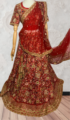 This exquisite red lehenga choli crafted from luxurious raw silk showcases intricate resham, zardosi, beads, sequins, and cut dana floral embroidery. The heavily embellished hemline and delicate cream butti accents enhance its sophisticated charm. Complete with a matching embroidered net dupatta featuring floral buttis and an elegant border, and a stitched blouse piece adorned with coordinating floral motifs, for wedding and bridal, pakistani, bangladeshi, indian, sri lankan.