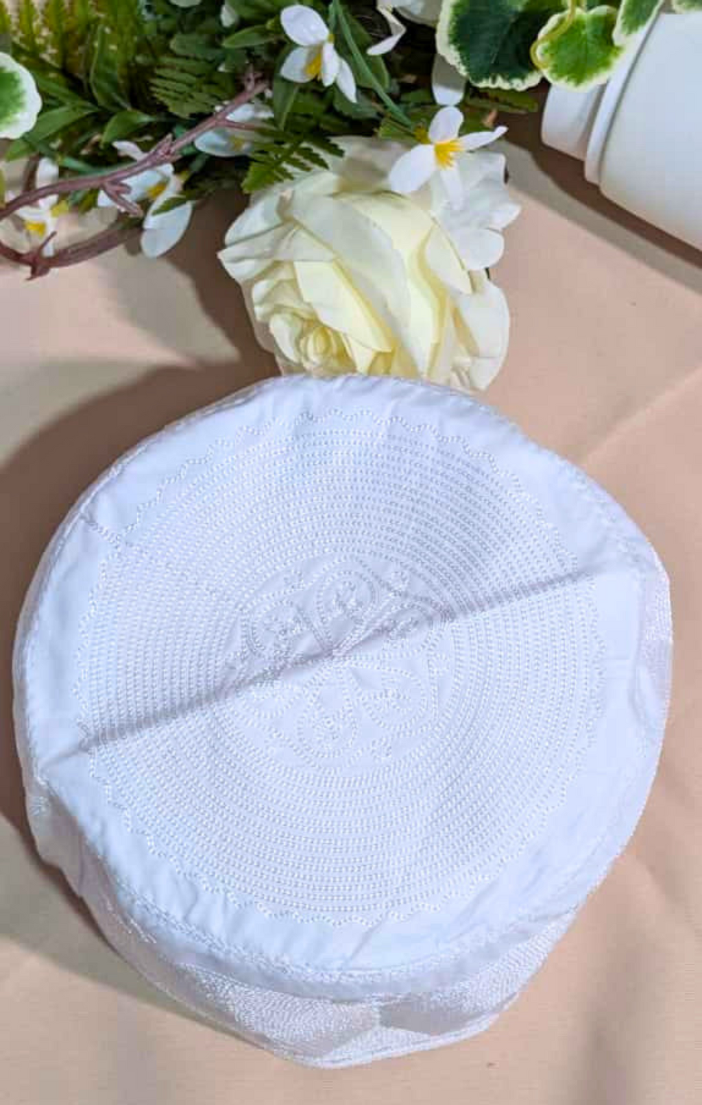 White round fabric pad on a beige surface with flowers in the corner
