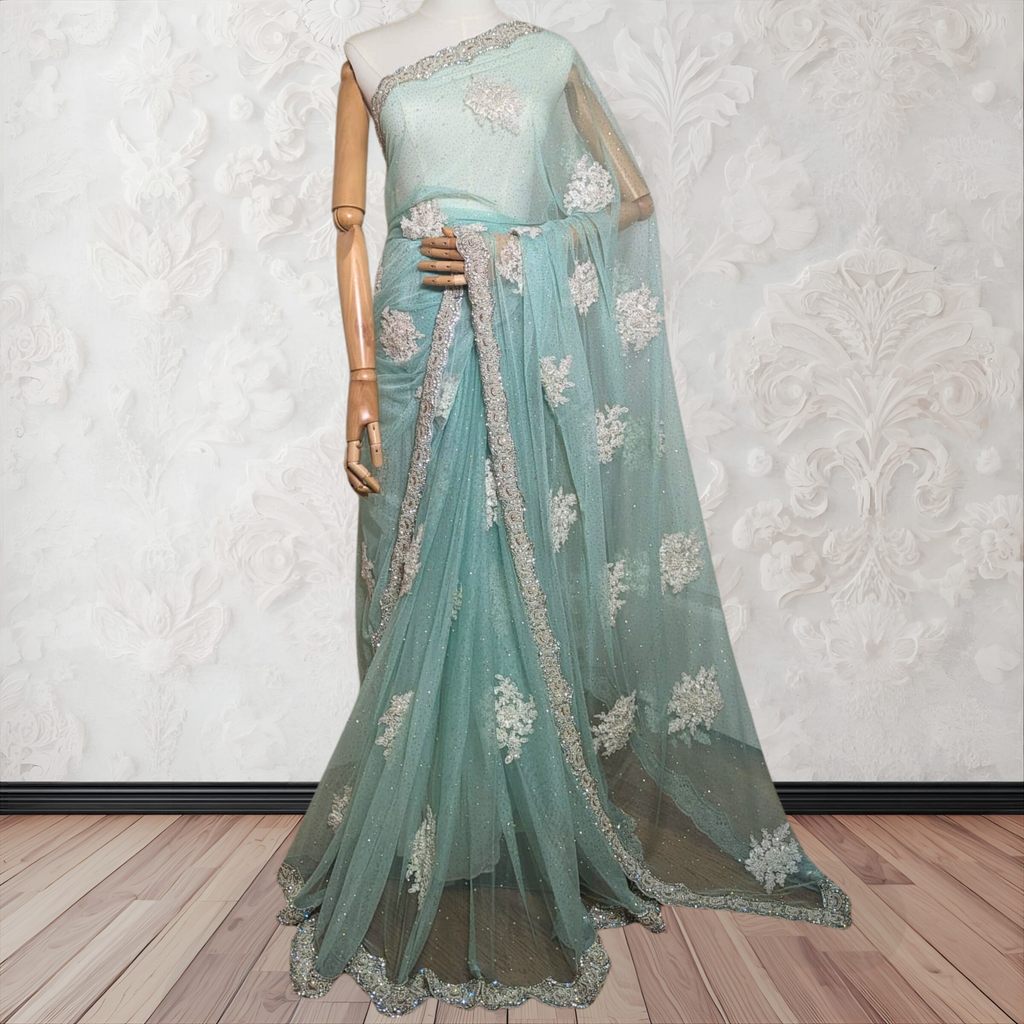 Teal saree with floral embroidery on a mannequin against a white wall.