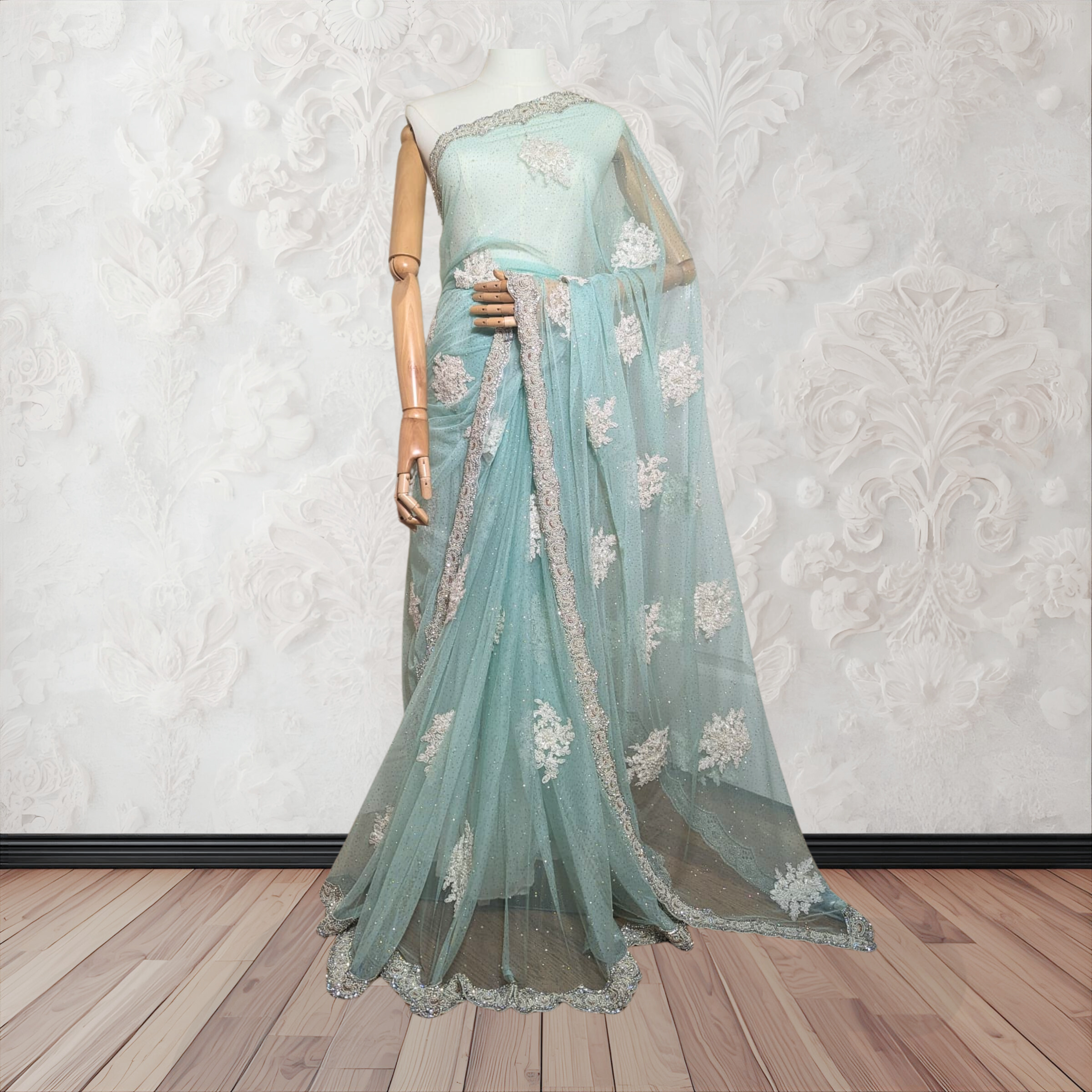 Light blue saree with white floral patterns on a mannequin against a white wall.