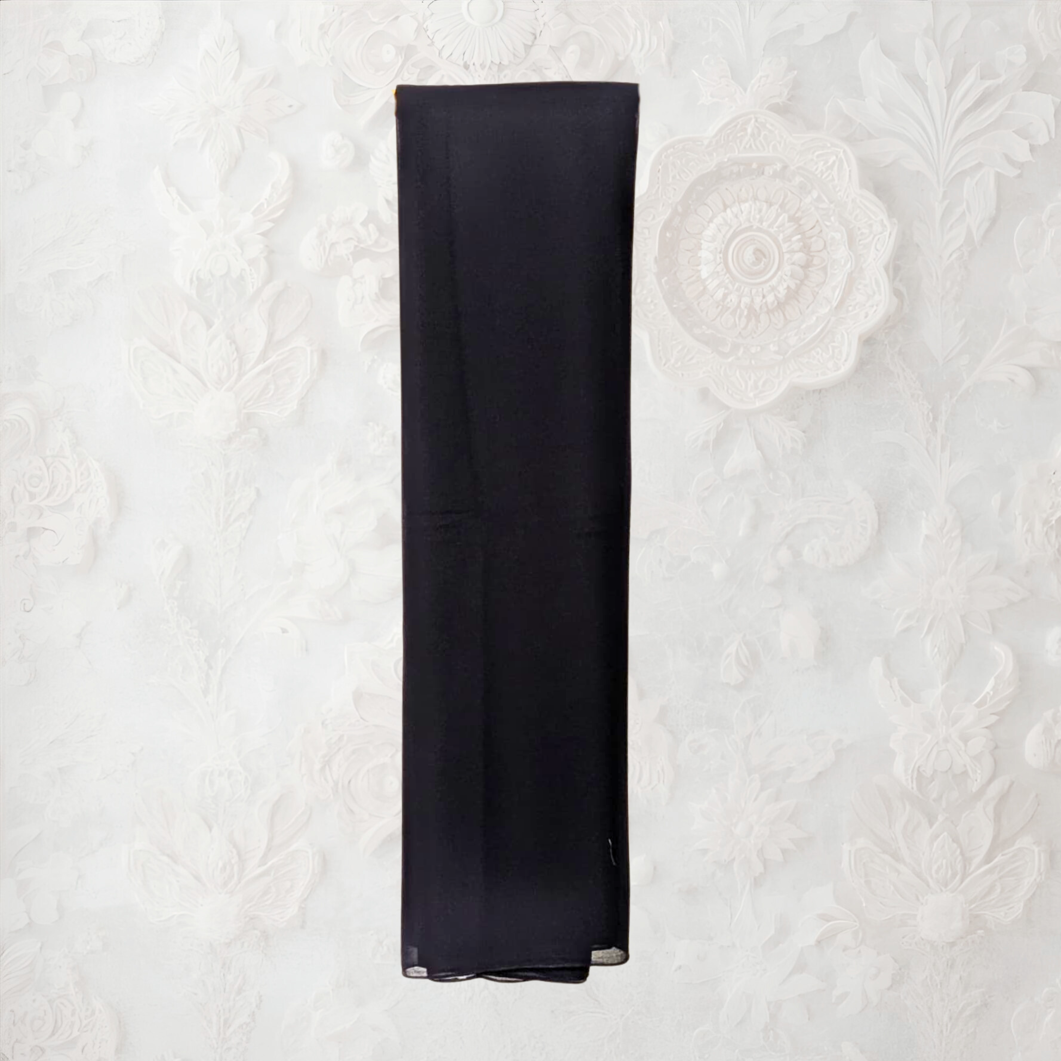 Black napkin on a textured white surface with a decorative flower.