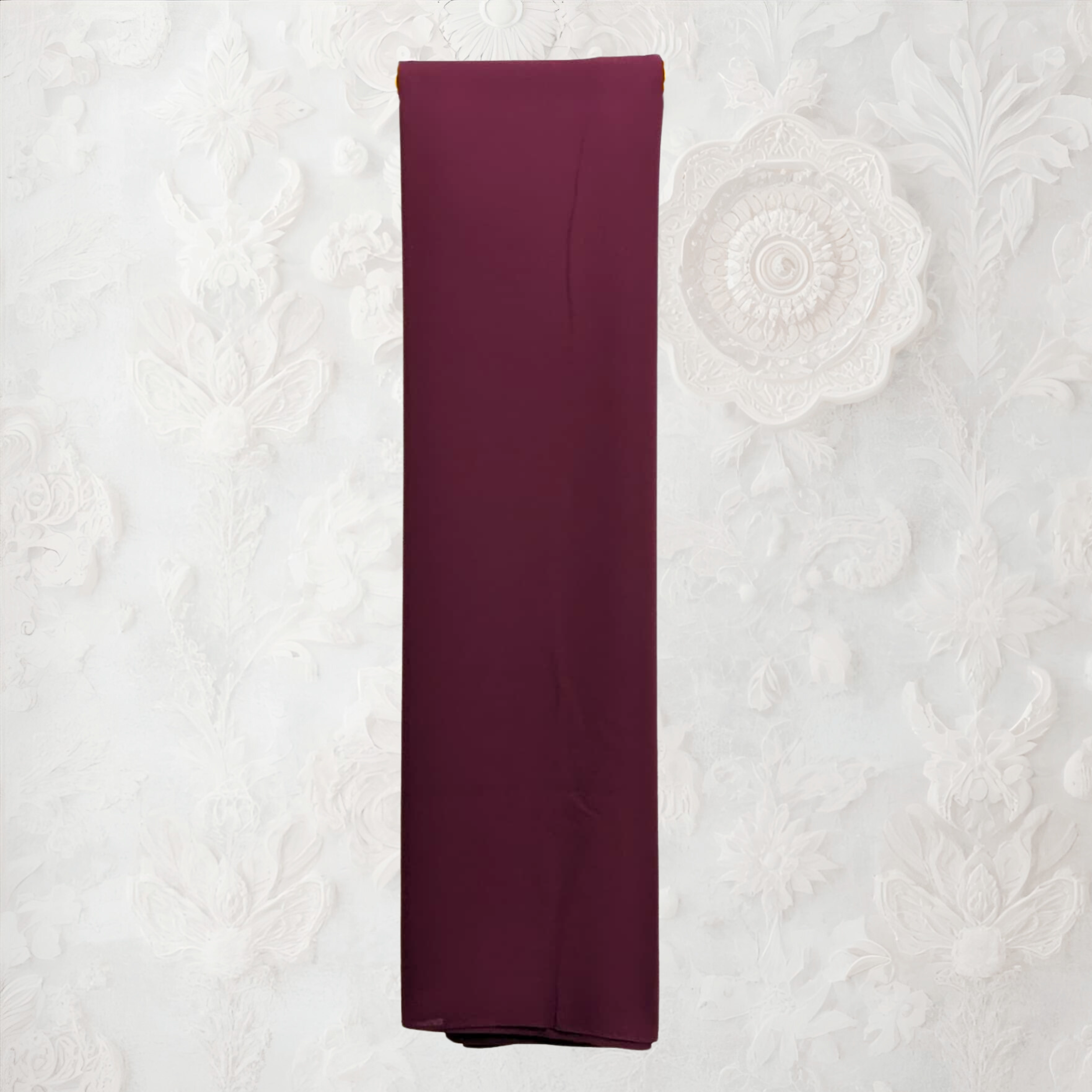 coffee color fabric draped over a yellow garment rack against a white wall. fabric on a textured white background