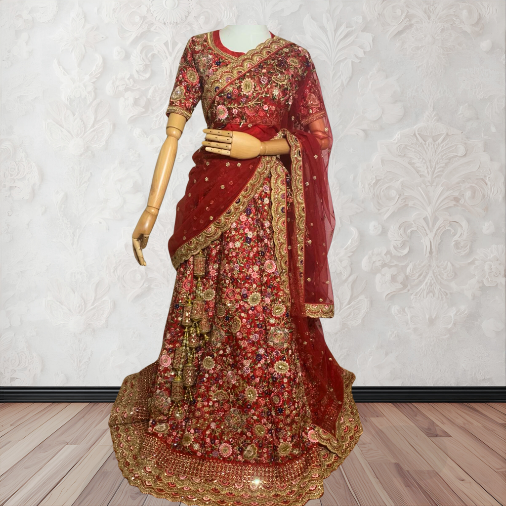 This exquisite red lehenga choli crafted from luxurious raw silk showcases intricate resham, zardosi, beads, sequins, and cut dana floral embroidery. The heavily embellished hemline and delicate cream butti accents enhance its sophisticated charm. Complete with a matching embroidered net dupatta featuring floral buttis and an elegant border, and a stitched blouse piece adorned with coordinating floral motifs, for wedding and bridal, pakistani, bangladeshi, indian, sri lankan.
