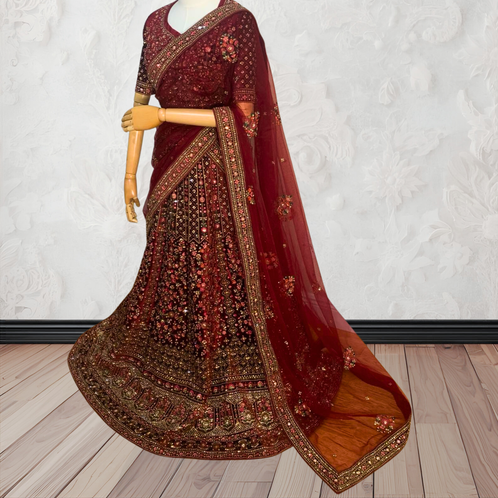 Maroon Lehenga with gold embroidery on a mannequin against a white wall. traditional desi, indian bridal ware for wedding. 