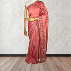 Pink saree with black embroidery on a mannequin against a white wall.