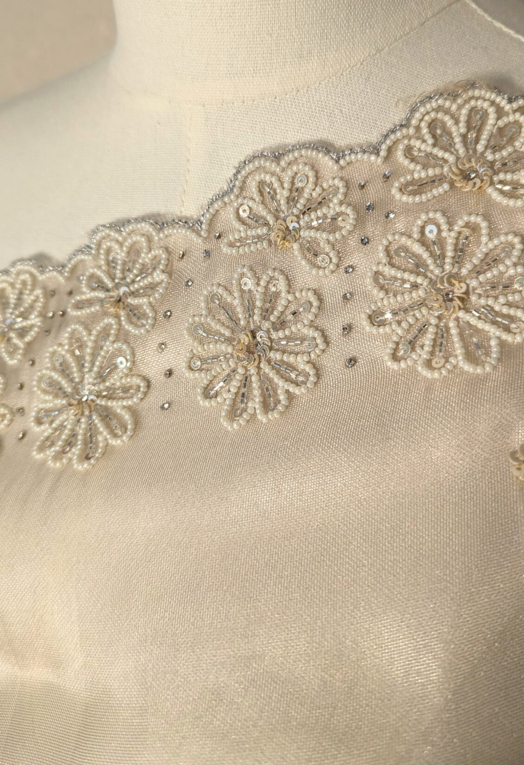 Mannequin wearing a beige saree with lace details against a white wall.