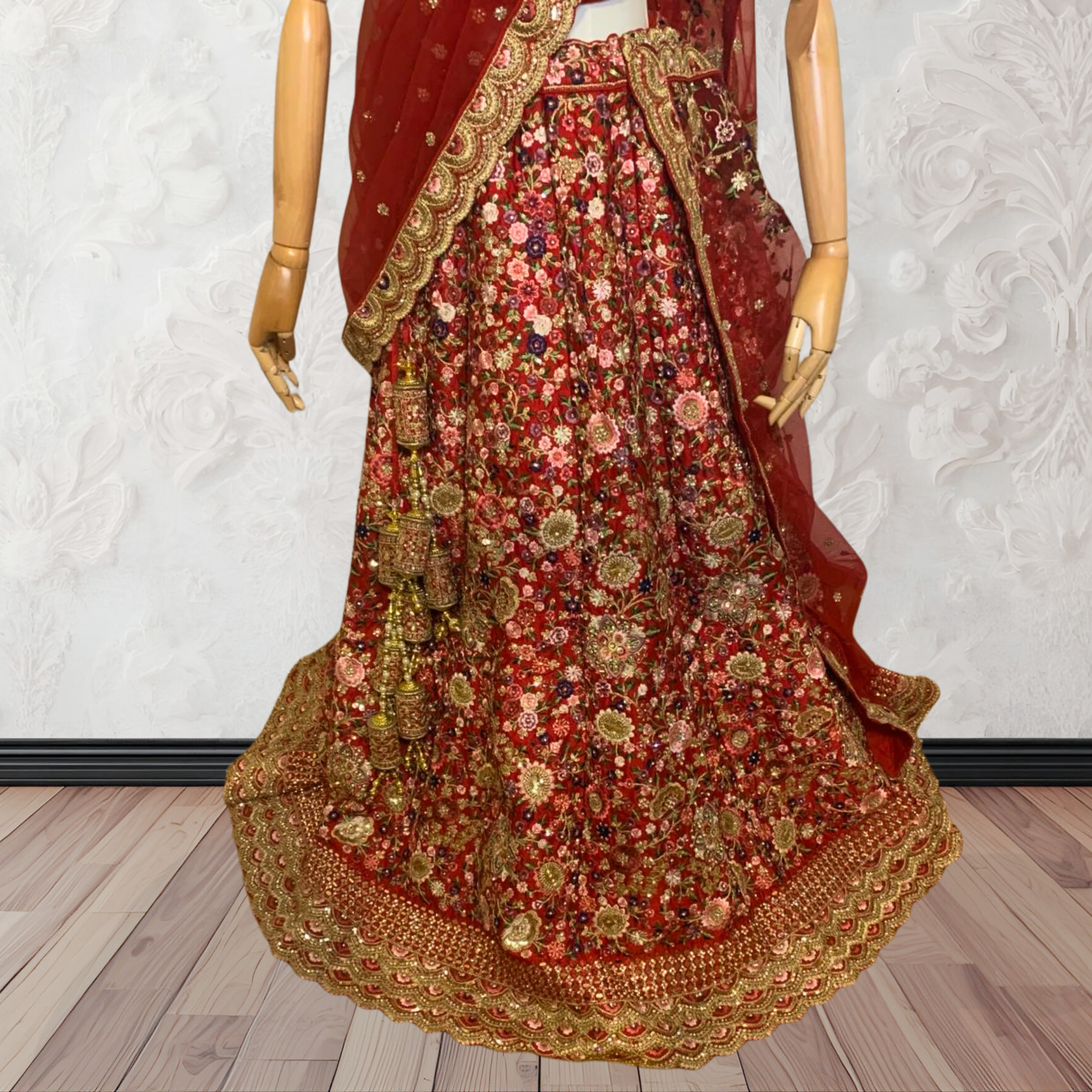 This exquisite red lehenga choli crafted from luxurious raw silk showcases intricate resham, zardosi, beads, sequins, and cut dana floral embroidery. The heavily embellished hemline and delicate cream butti accents enhance its sophisticated charm. Complete with a matching embroidered net dupatta featuring floral buttis and an elegant border, and a stitched blouse piece adorned with coordinating floral motifs, for wedding and bridal, pakistani, bangladeshi, indian, sri lankan.