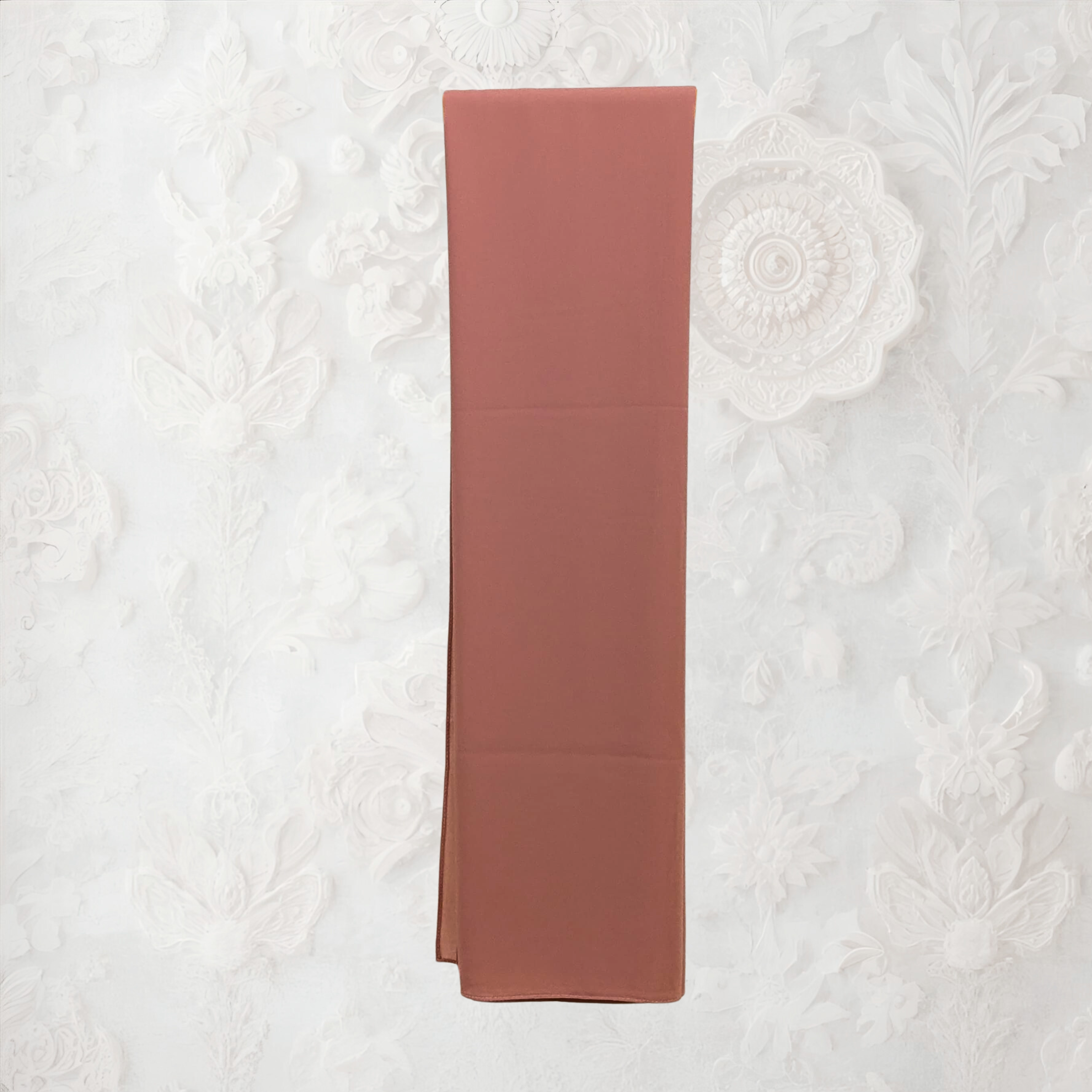 Folded pink fabric on a textured white background chiffon hijab
