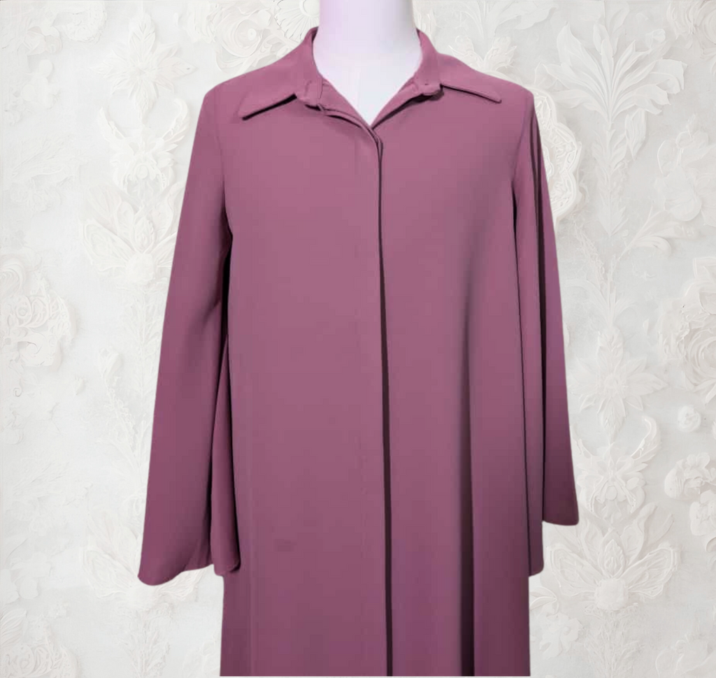 Purple coat on a mannequin against a white textured wall with wooden floor.