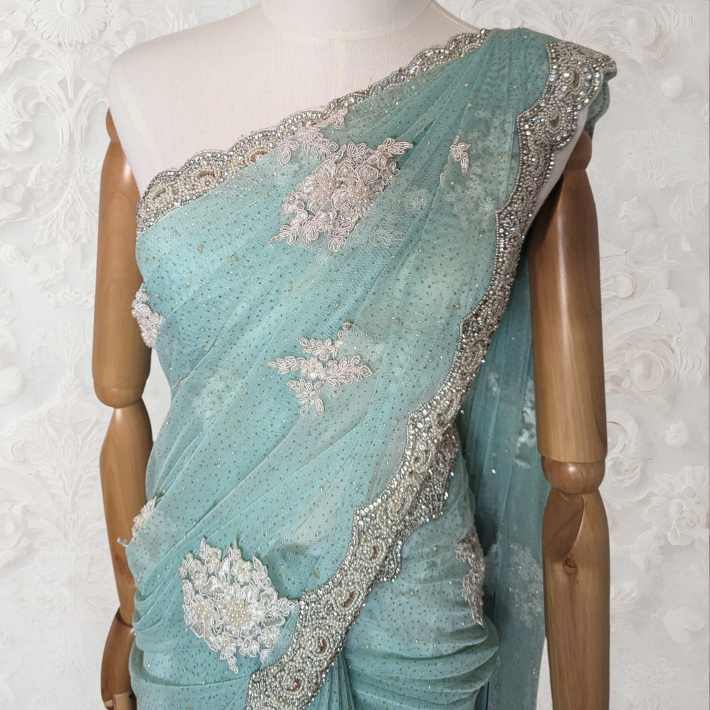 Teal saree with silver embroidery on a mannequin against a white background
