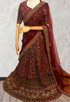 Maroon Lehenga with gold embroidery on a mannequin against a white wall. traditional desi, indian bridal ware for wedding. 