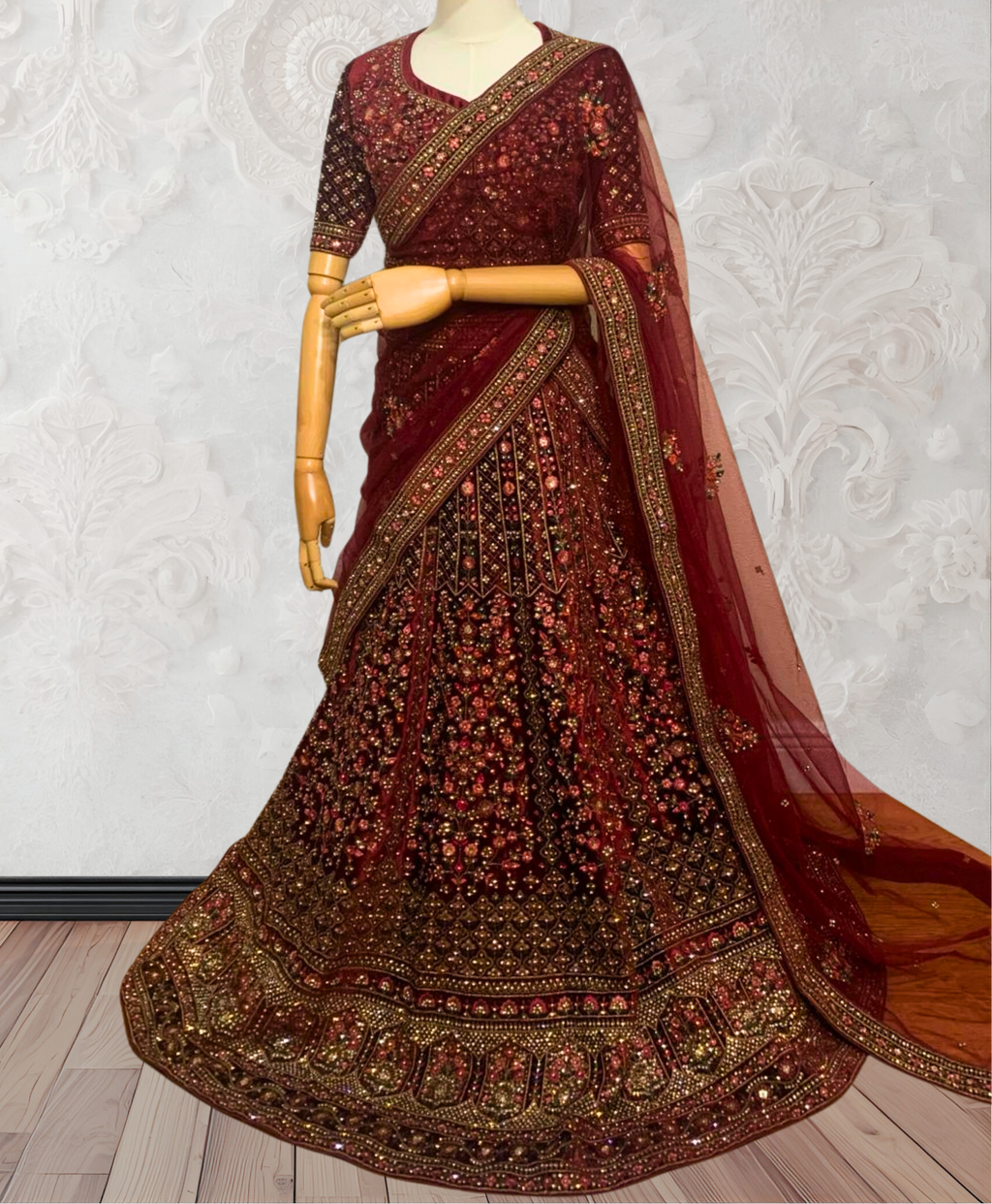Maroon embroidered traditional outfit on a mannequin against a white textured wall.