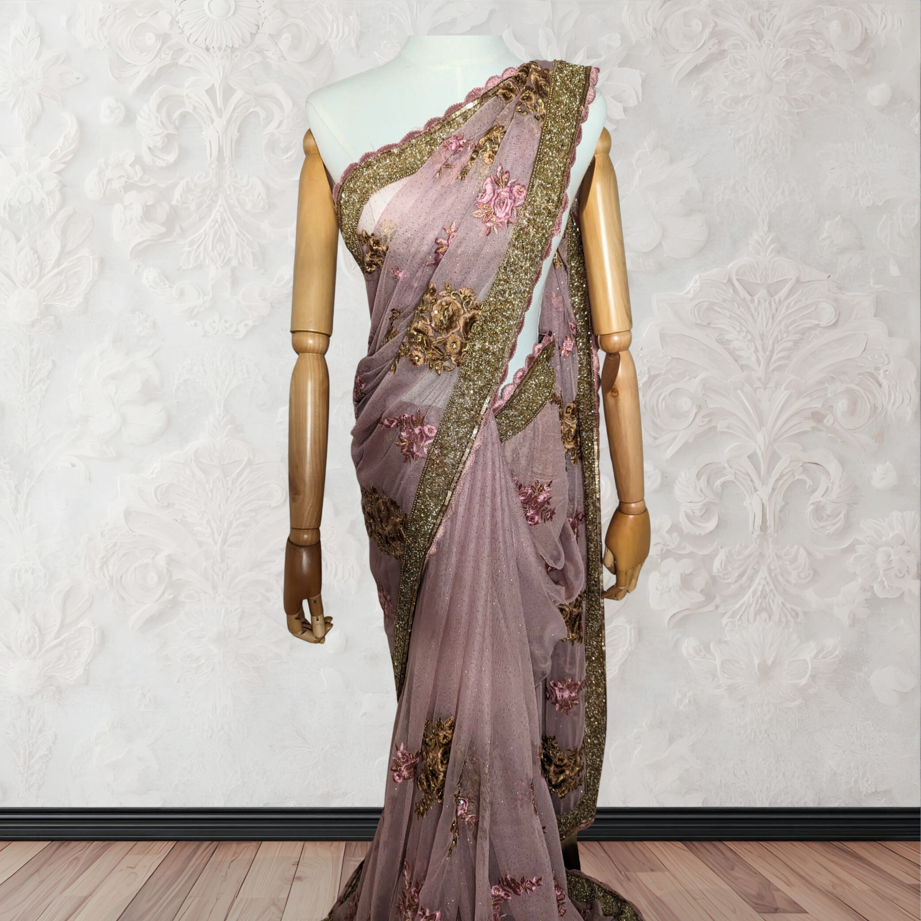 Saree with floral embroidery on a mannequin against a white wall.