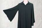 Black cape on a mannequin against a light-colored wall with wooden floor.