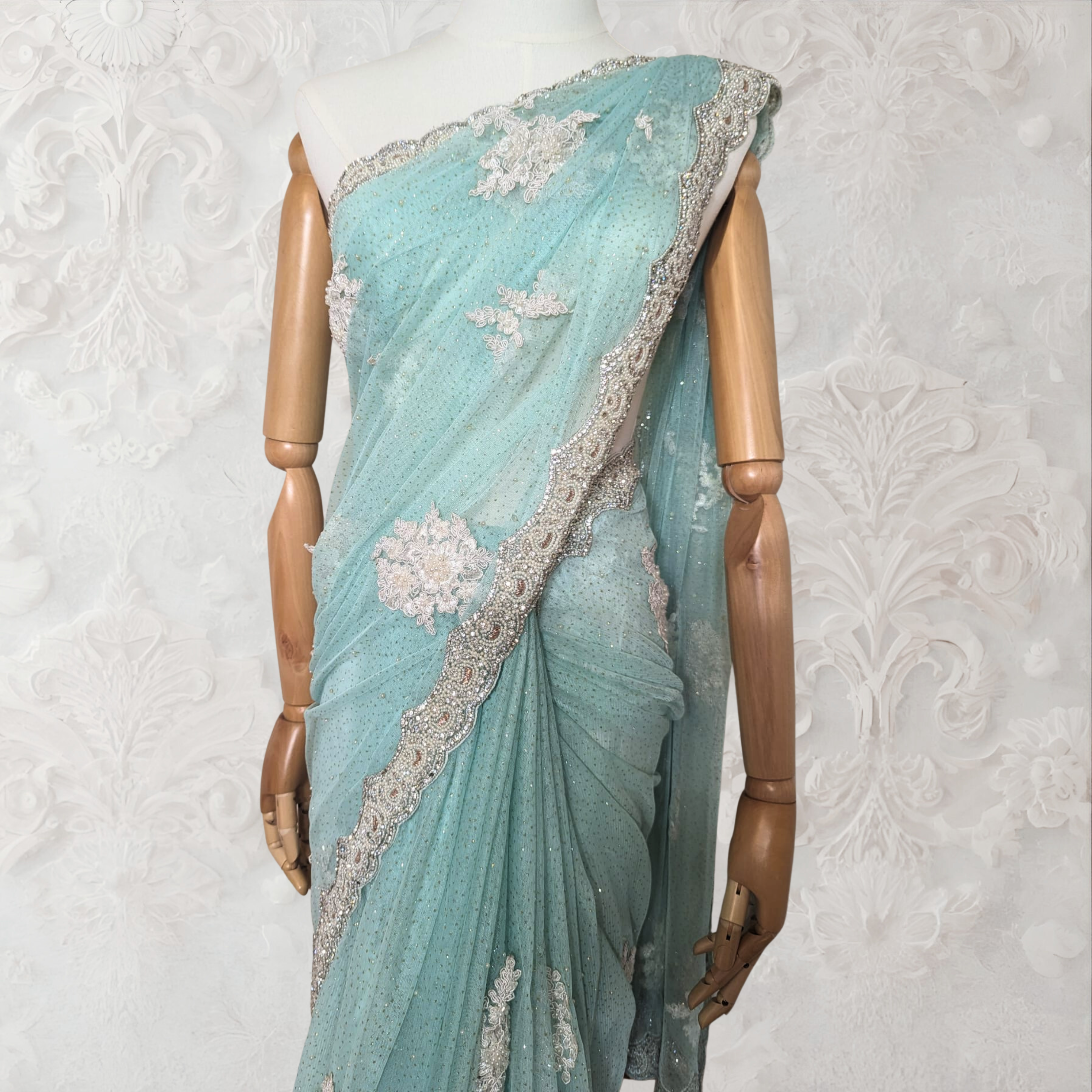 Light blue saree with silver border on a mannequin against a white background