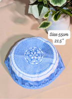 Blue and white decorative item on a beige surface with green leaves in the background