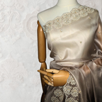 Mannequin wearing a beige saree with floral lace details against a textured white background