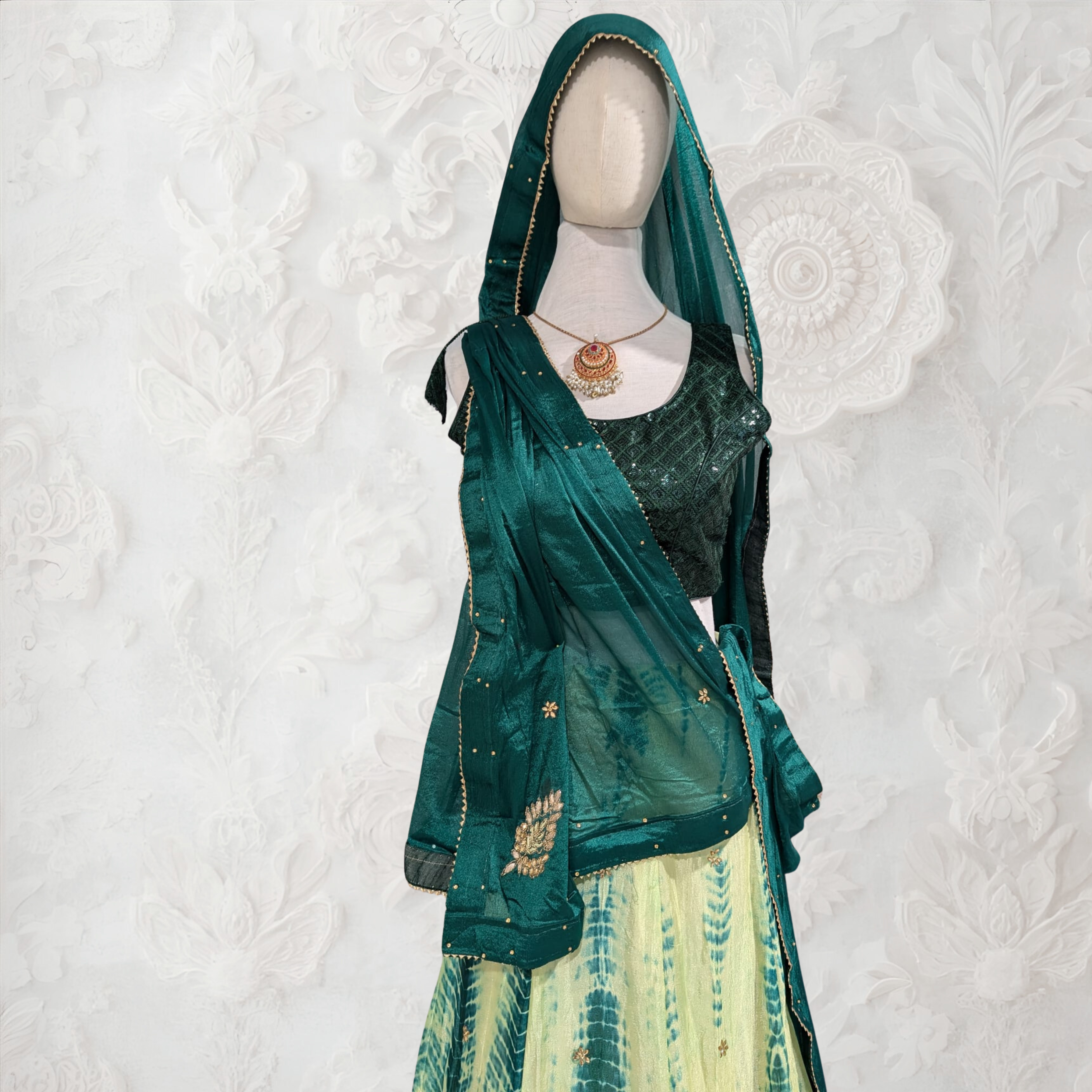 Mannequin wearing a green saree with a white background