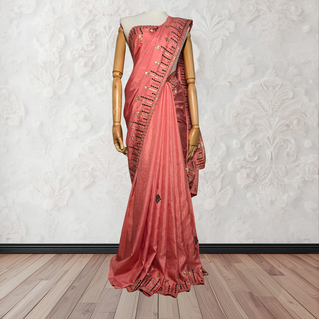 Pink saree with gold patterns on a mannequin against a white wall.