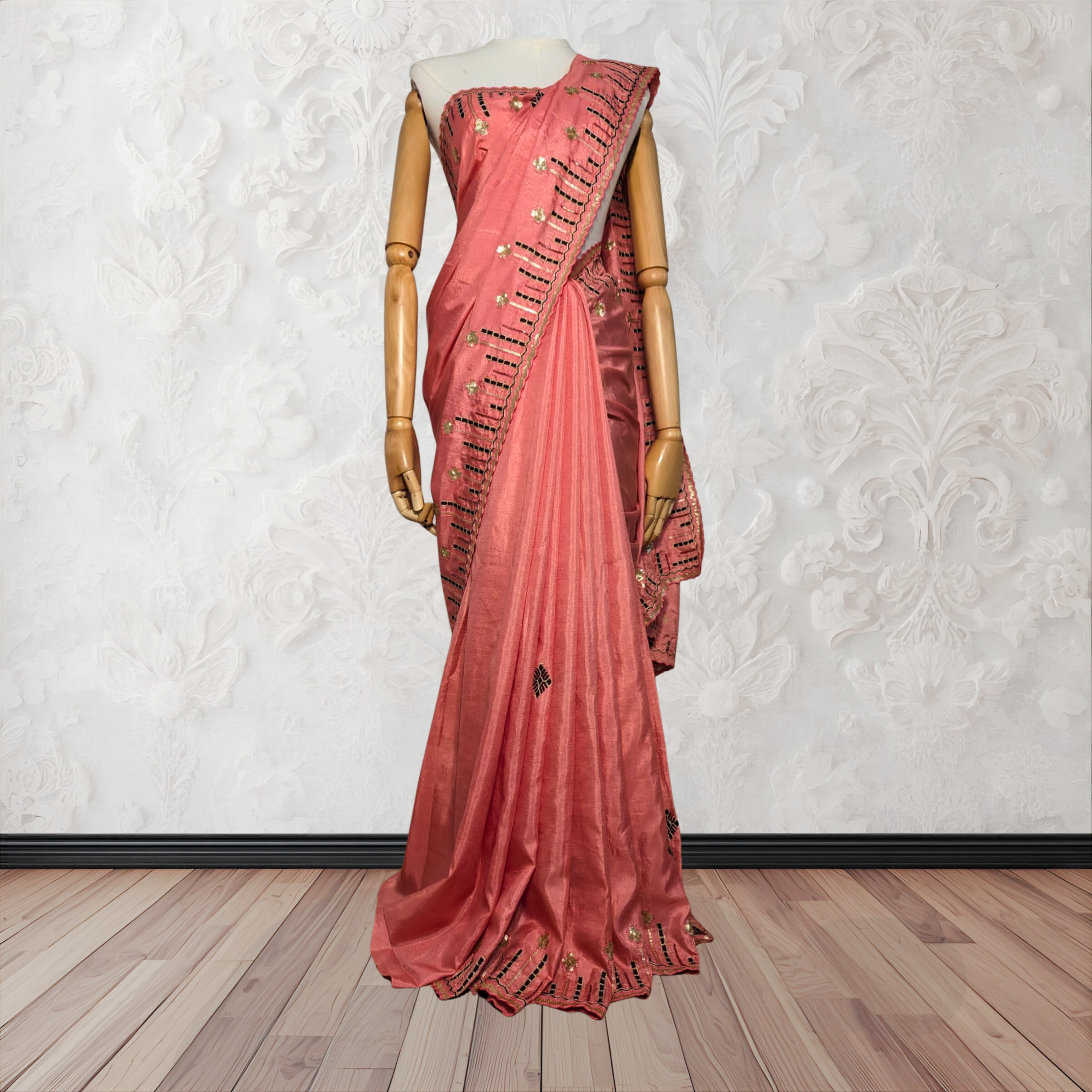 Pink saree with gold patterns on a mannequin against a white wall.