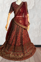 Maroon Lehenga with gold embroidery on a mannequin against a white wall. traditional desi, indian bridal ware for wedding. 