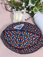 Woven fabric with a geometric pattern on a light pink surface, with a small plant in the background.