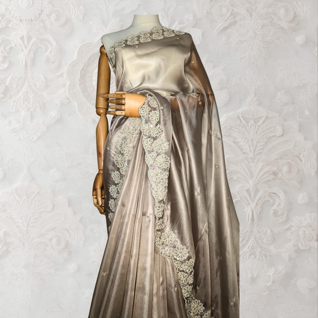 Silver saree with intricate designs on a mannequin against a textured white background