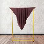 Brown clothing rack with a coffee fabric draped over it against a white wall.