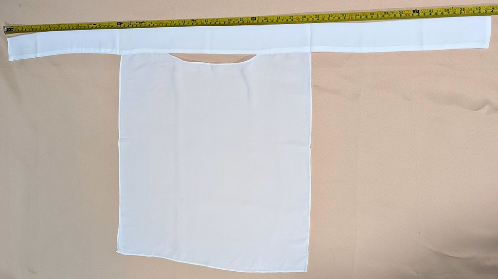 White fabric with a pocket on a beige background, with a measuring tape at the top.