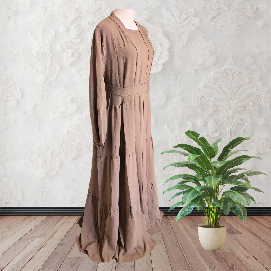 Brown dress on a mannequin with a plant on a wooden floor against a white wall