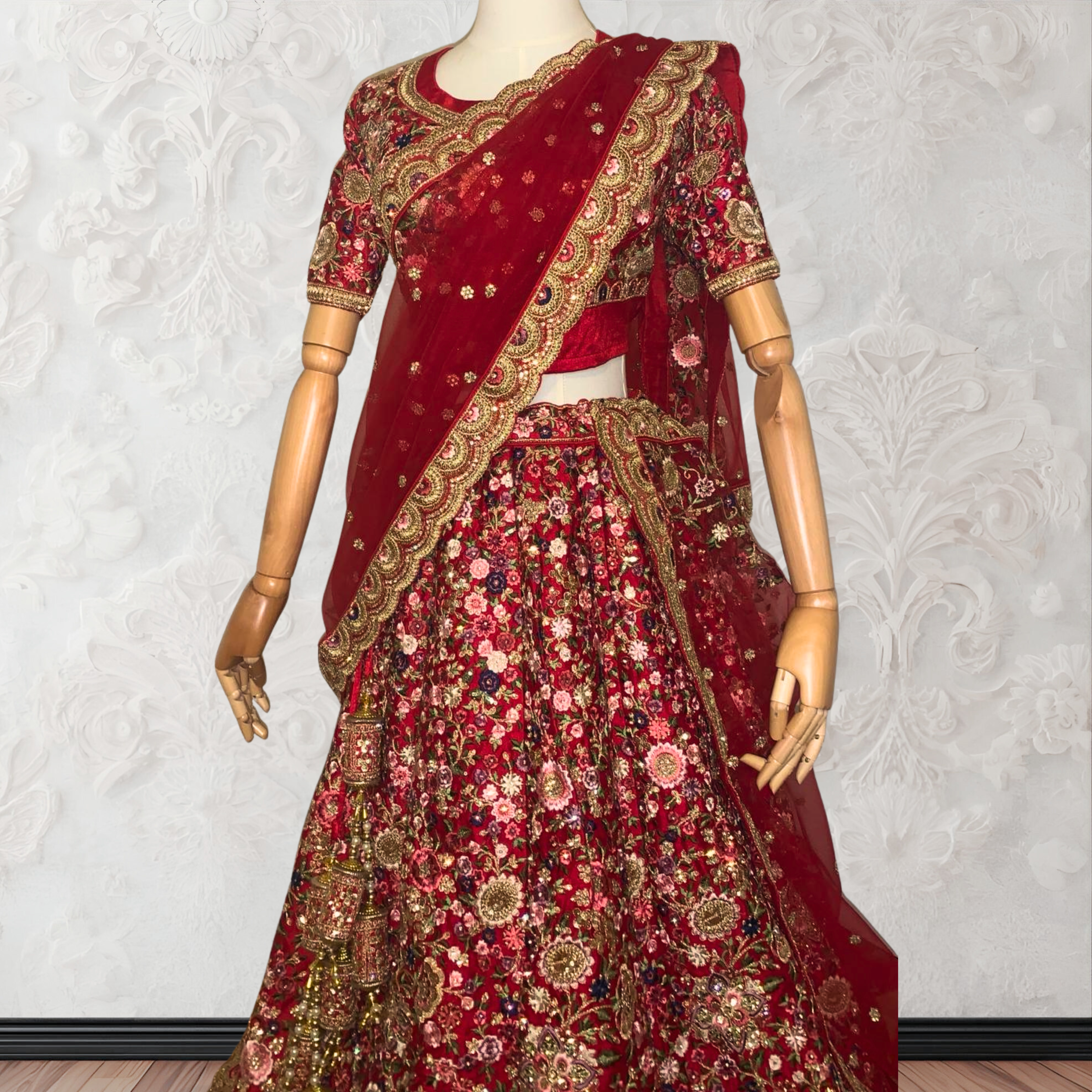This exquisite red lehenga choli crafted from luxurious raw silk showcases intricate resham, zardosi, beads, sequins, and cut dana floral embroidery. The heavily embellished hemline and delicate cream butti accents enhance its sophisticated charm. Complete with a matching embroidered net dupatta featuring floral buttis and an elegant border, and a stitched blouse piece adorned with coordinating floral motifs, for wedding and bridal, pakistani, bangladeshi, indian, sri lankan.
