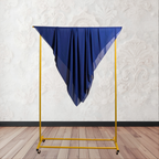 Yellow clothing rack with a blue fabric draped over it against a white wall.