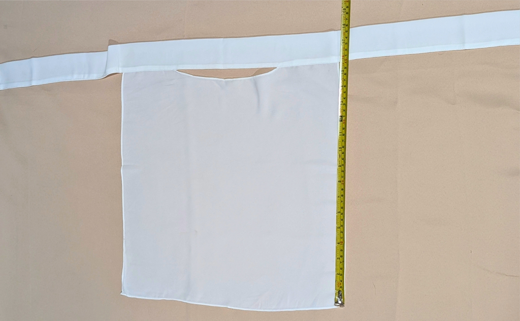 White fabric with a cutout on a beige background, with a measuring tape indicating dimensions.