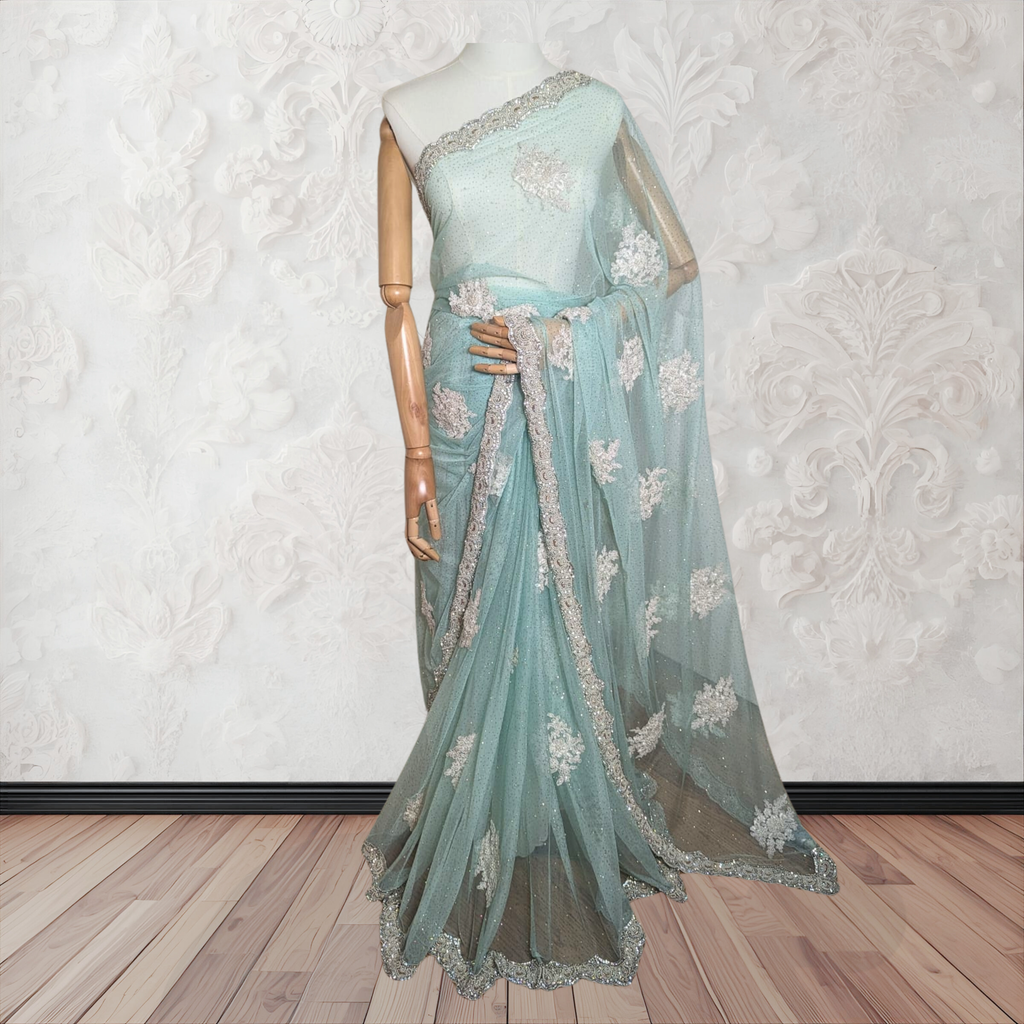 Light blue saree with floral patterns on a mannequin against a white wall.