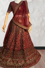 Maroon Lehenga with gold embroidery on a mannequin against a white wall. traditional desi, Indian, Pakistani, Bangladeshi, Sri lankan bridal ware for wedding. 